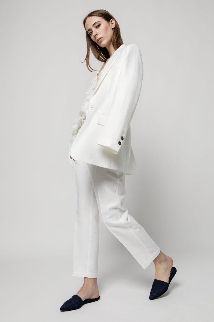 modella vestita in completo bianco giacca e pantalone e scarpe mule sabot a punta in denim colore nero