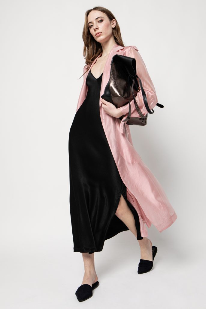 modella con abito nero e trench rosa in organza borsa sotto braccio e ai piedi mule sabot di denim con la punta